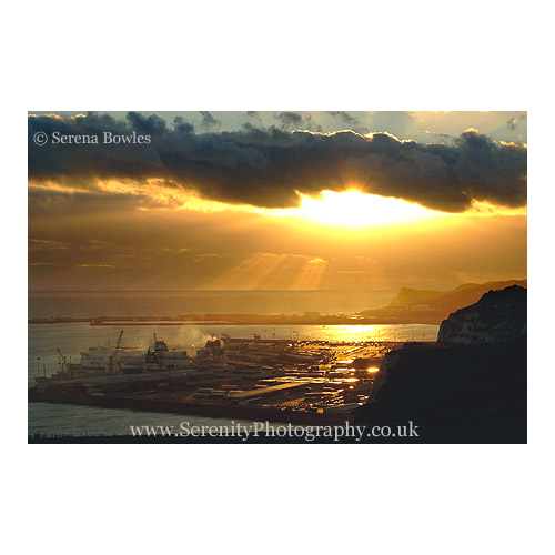 The sun breaks through a gap in the clouds and shines down on Dover docks. Taken from the famous White Cliffs of Dover, Kent.
